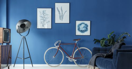 Mat blå malet væg med malerier og cykel