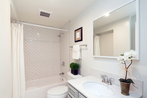 Hvidt badeværelse med stort spejl og badekar.