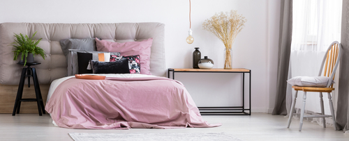 Soveværelse indrettet med lyserødt sengetæppe.