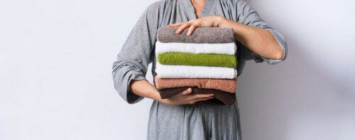 Person holder en bunke håndklæder 
