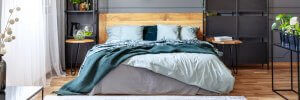 Et billede, der viser en seng i et moderne soveværelse med trægulve.