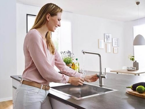 Kvinde tager vand fra en køkkenvandhane 