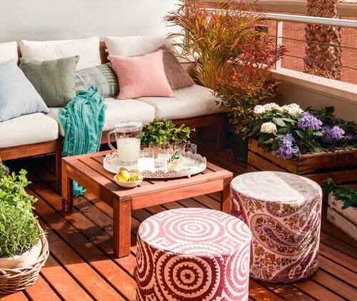 En lille terrasse dekoreret med møbler og planter.