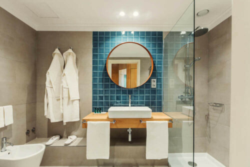 badeværelse med rundt spejl og blå fliser
