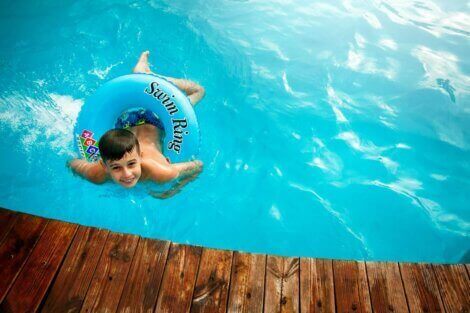 dreng svømmer i pool i haven