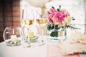 Blumenstraß in einer Vase neben zwei Weingläsern