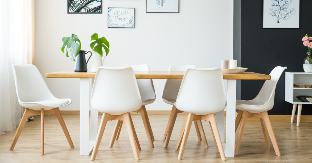 Sillas de comedor entorno a la mesa de color blanco y patas de madera