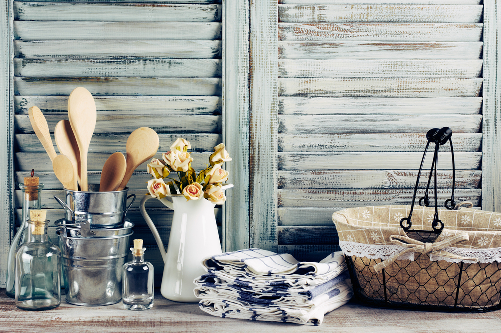 Elementos de época vintage para decorar tu cocina de madera: cesto, jarrón con flores, manteles, cucharones de madera.
