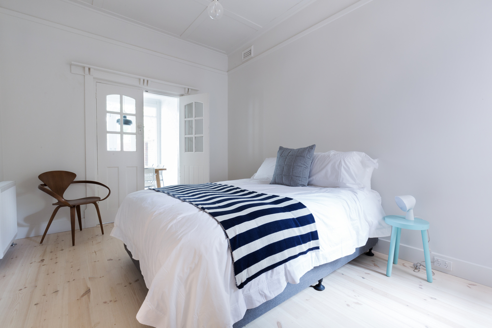Habitación básica para invitados decorada al estilo nórdico en blanco con detalles azules.