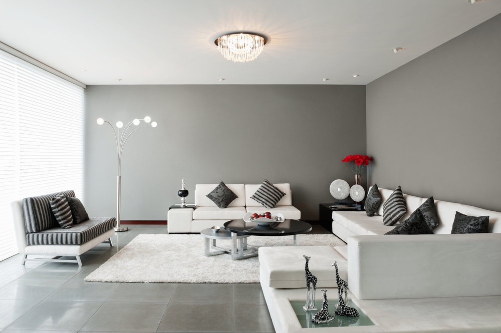 Paredes del salón en gris claro combinado con sofás en blanco y alfombra de pelo blanco.