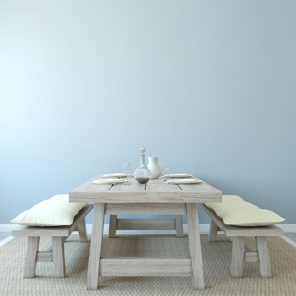 Mesa comedor rústica de colores grises con bancos de madera con cojines en blanco.