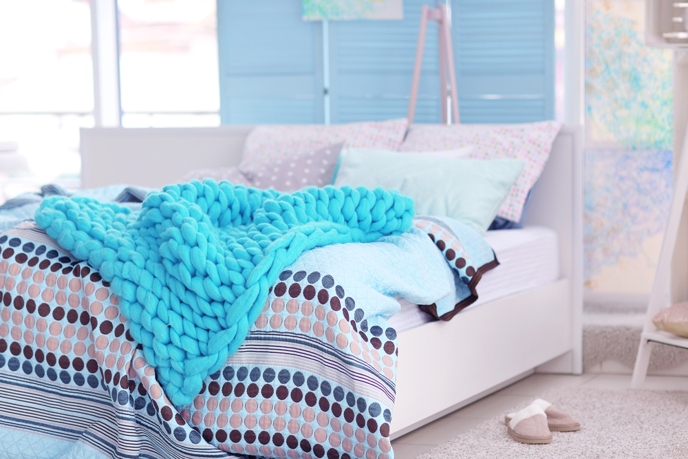 Plaid de lana azul sobre cama.