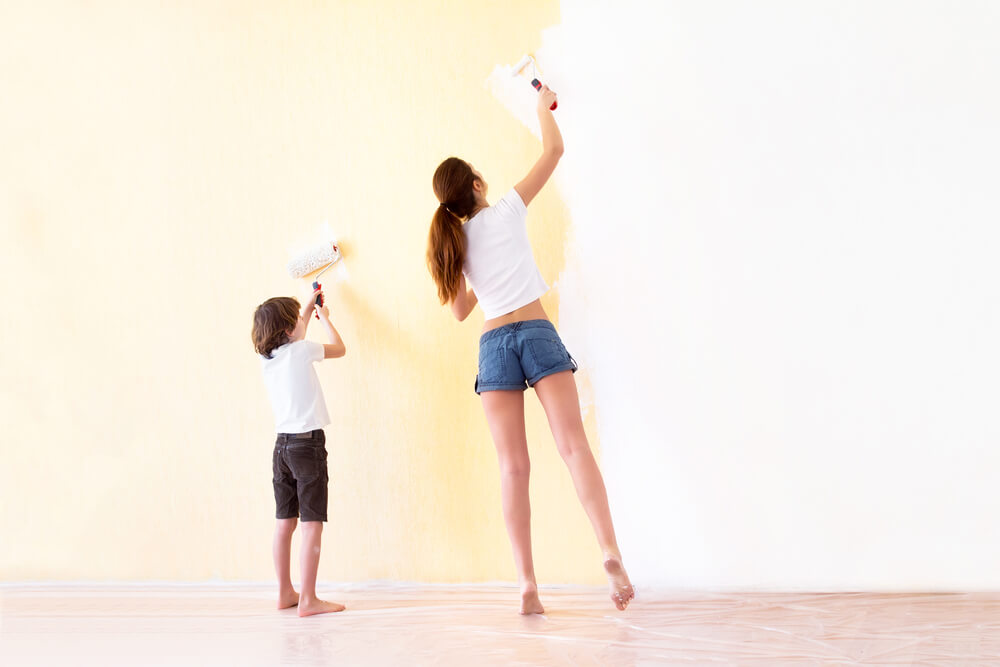 Madre e hijo pintando una pared de casa.