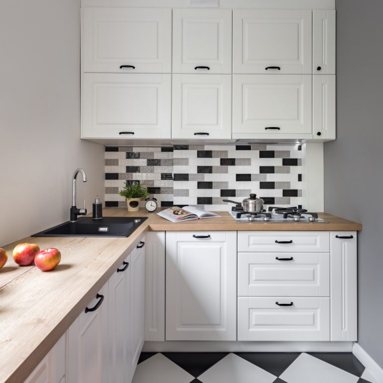 cucina bianca con piano lavoro in legno chiaro e mattonelle bianche e nere