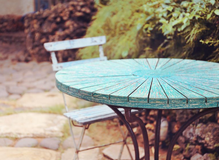 giardino con tavolo in legno azzurro con base in metallo e sedia