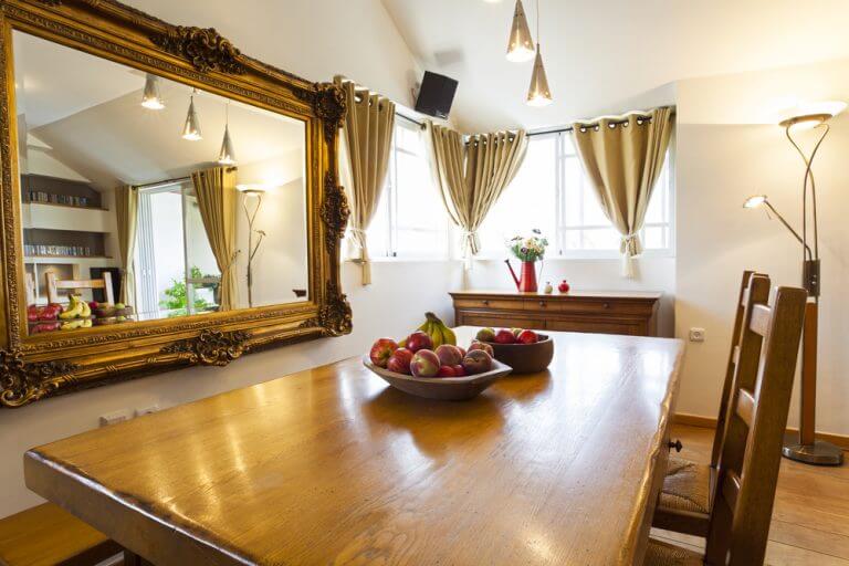Cucina con specchia grande con cornice dorata e tavolo in legno 