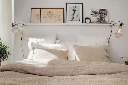 Camera da letto bianca con testata e mensola con quadri