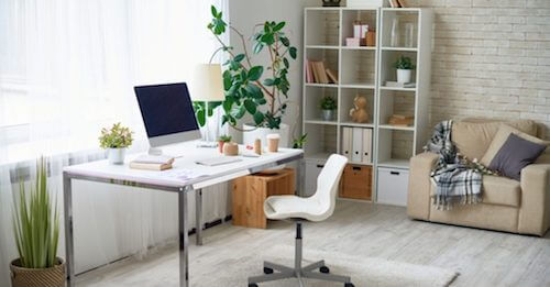 tavolo e sedia bianchi con libreria e divano e piante