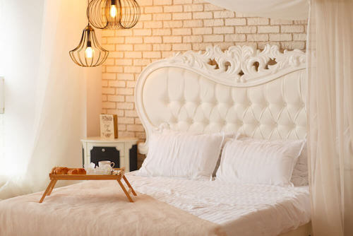 camera da letto con letto testata comodino e pareti bianche