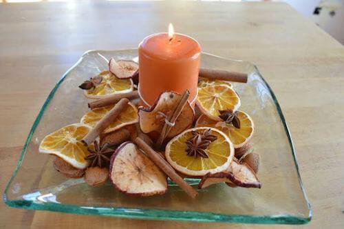 centrotavola con candela mele arance secche e bastoncini di cannella