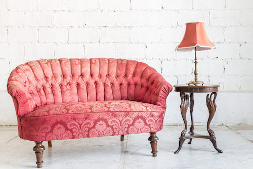 divano rosa con schienale trapuntato tavolino con lampada