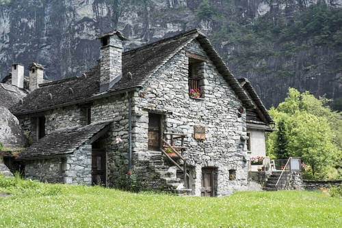 Casa di campagna in pietra affacciata su un prato.