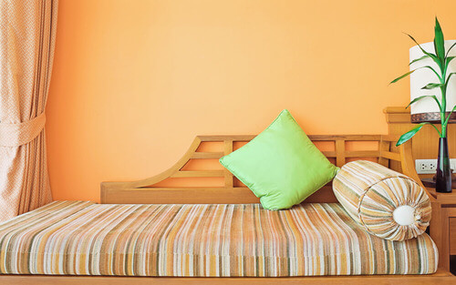 Divano letto con parete arancione.