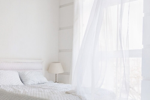Total white: camera da letto e tende bianche.