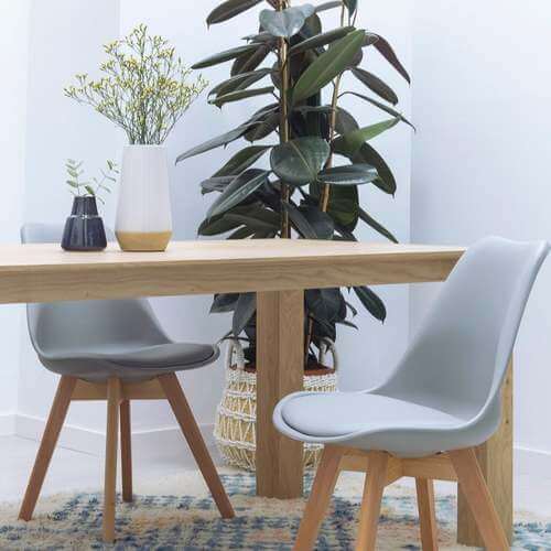 Mobile in legno chiaro con pianta e sedie grigie.