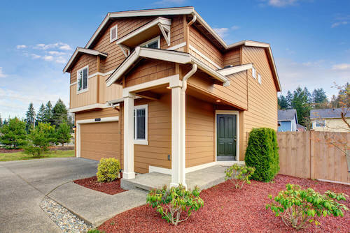 Colori della facciata. Casa in legno con facciata color marrone e porta verde.