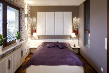 Camera da letto piccola con testiera bianca.
