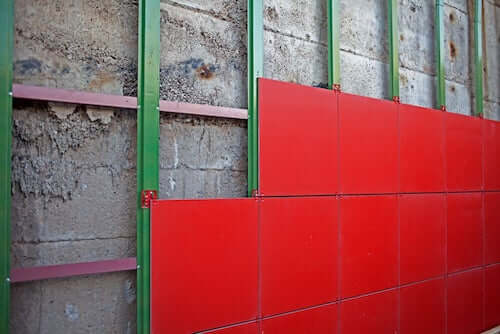 Facciate ventilate. Facciata ventilata con pannelli rossi installata su muro di cemento.