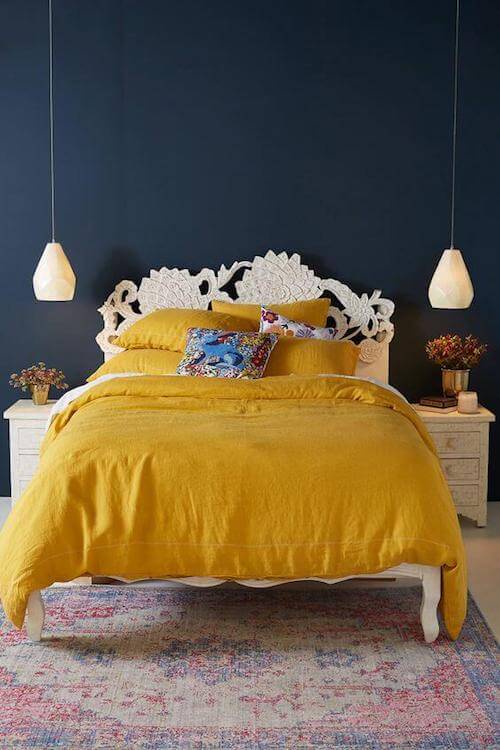 Camera da letto con pareti blu e biancheria da letto gialla.