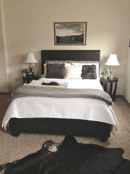 Letto nero con coperte e cuscini bianchi e grigi.