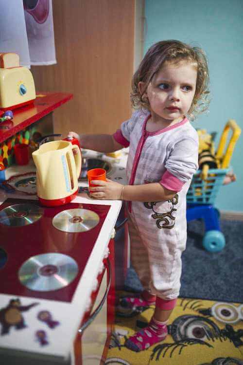Bambina che gioca con una cucina giocattolo.