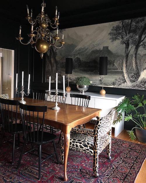 Sala da pranzo elegante con tappeto persiano, lampadario dorato e poltrone con stampe animalier.