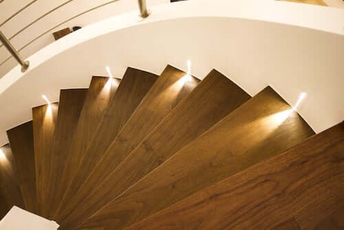 Luci a livello del suolo per illuminare gli scalini di una scala in legno.