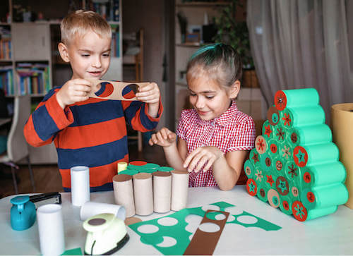 Bambini che fanno dei lavori manuali per creare delle decorazioni natalizie.