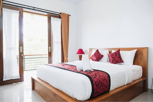 Camera da letto con cuscini e abat-jour rossi.