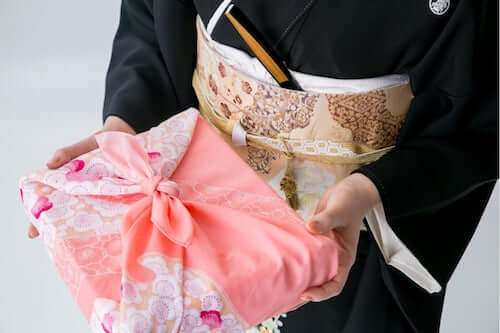 Donna giapponese che ha in mano un regalo confezionato con la tecnica del Furoshiki.
