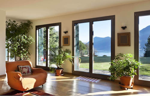 Soggiorno con pavimenti in legno e ampie vetrate decorato con le piante.