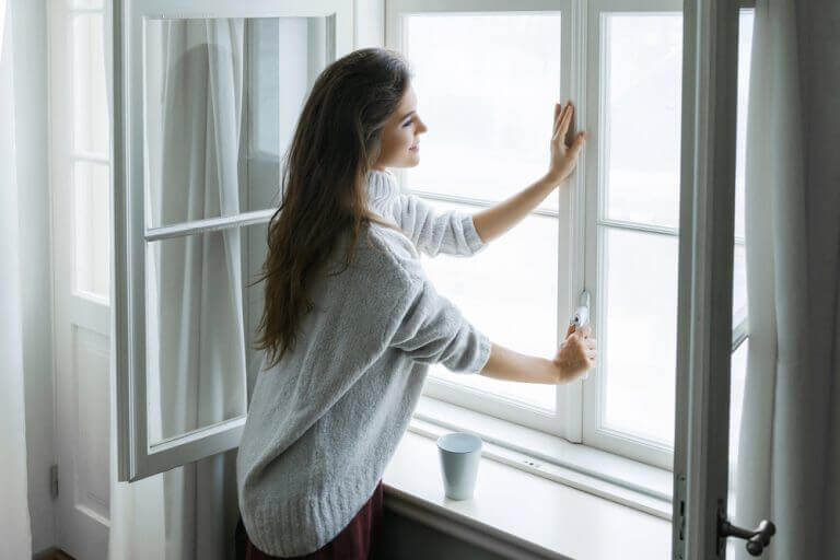 Vrouw opent gordijnen en het raam