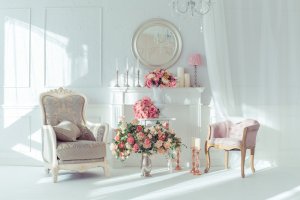 Pembe çiçeklerle dolu şömineli beyaz oda