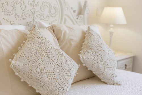 beyaz yatak örtüsü üzerinde tığ işi yastıklar