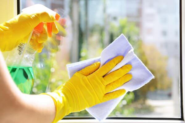Sarı temizlik eldiveniyle cam silen kadın