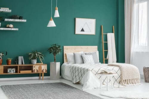 Zümrüt yeşili duvarları olan beyaz ve ahşap tonlarında yatak odası