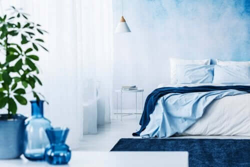 Açık mavi duvarlı vazo ve yatak örtülerinde mavi tonları kullanılmış oda