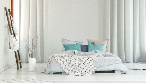 A white floor level bed with turquoise accessories