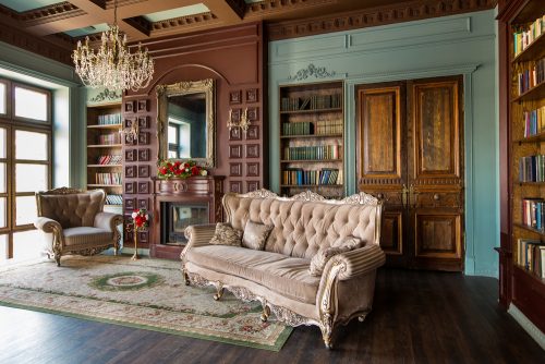 A Victorian style living room should include upholstered sofas, rugs and a chandelier