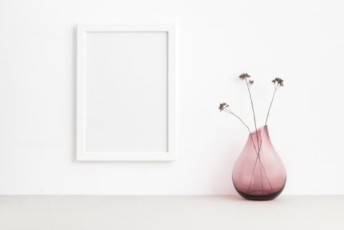 Pink transparent vase with dried flowers sitting on the floor